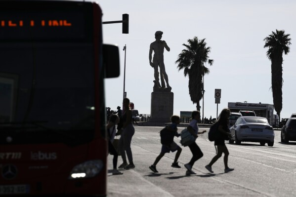 FILE - Children cross Avenue du Prado with the David Statue in the background in Marseille, France, Monday, Sept. 11, 2023. The word "Quoicoubeh!," became super popular this year with French teenagers who used it to annoy their elders, though it doesn't have a real meaning. It's simple: A teen says something inaudible, hoping that parents or teachers will answer "Quoi?" or "What?" The response : "Quoicoubeh!" (AP Photo/Pavel Golovkin, File)
