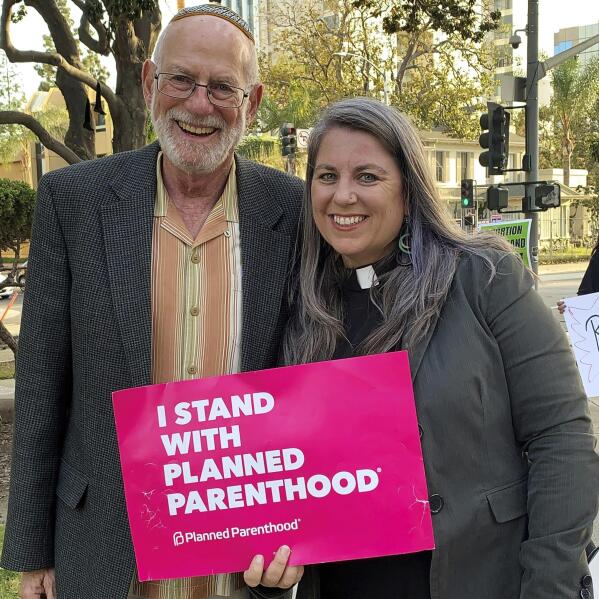 In this photo provided by Felicity Figueroa, Rabbi Stephen Einstein, left, founding rabbi of Congregation B’nai Tzedek in Fountain Valley, Calif., stands with the Rev. Sarah Halverson-Cano, senior pastor of Irvine United Congregational Church in Irvine, Calif., at a rally supporting abortion access, in Santa Ana, Calif., May 3, 2022. (Felicity Figueroa via AP)