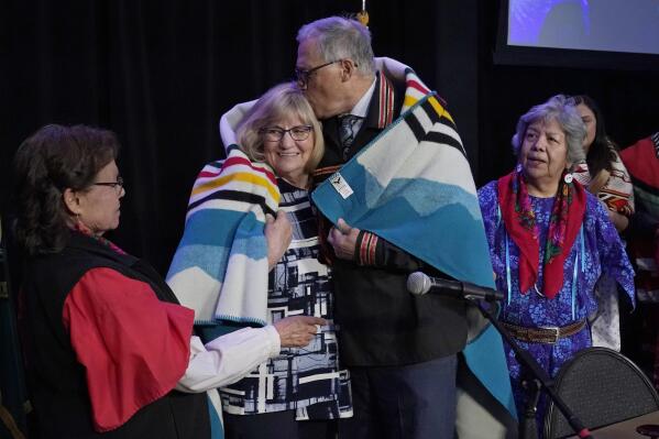 Washington Gov. Jay Inslee, second from right, kisses his wife Trudi, after they were presented a blanket in a ceremony after Inslee signed a bill that creates a first-in-the-nation statewide alert system for missing Indigenous people — particularly women, Thursday, March 31, 2022, in Quil Ceda Village, near Marysville, Wash., north of Seattle. The law creates a system similar to Amber Alerts, which are used for missing children in many states. (AP Photo/Ted S. Warren)