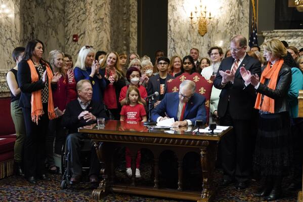 FILE - Washington Gov. Jay Inslee signs House Bill 1240, which prohibits the manufacture, importation, distribution and sale of semi-automatic assault-style weapons in the state, April 25, 2023, at the state Capitol in Olympia, Wash. A U.S. judge on Tuesday, June 6, rejected a request to block a new Washington state law banning the sale of certain semi-automatic rifles, one of three measures recently signed by Inslee in an effort to reduce gun violence. (AP Photo/Lindsey Wasson, File)