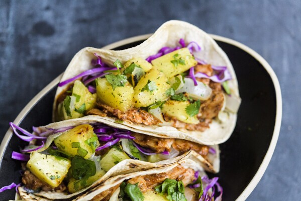This image released by Milk Street shows a recipe for tacos made with broiled pork tenderloin tenderized with fresh pineapple. (Milk Street via AP)