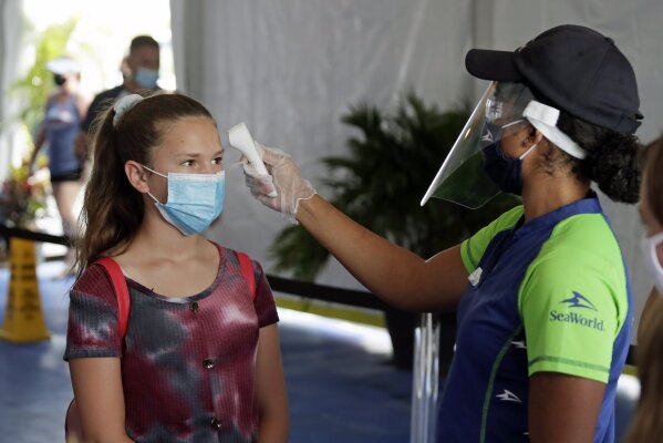 A guest has her temperature checked before entering SeaWorld as it reopens with new safety measures in place because of the coronavirus pandemic, Thursday, June 11, 2020, in Orlando, Fla. The park had been closed since mid-March to stop the spread of the new coronavirus. (AP Photo/John Raoux)