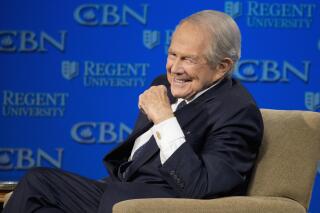 FILE - In this Feb. 24, 2016 file photo, Rev. Pat Robertson listens as Republican presidential candidate Donald Trump speaks at Regent University in Virginia Beach, Va.  The Christian Broadcasting Network says Pat Robertson is stepping down as host of the long-running daily television show the “700 Club.” Robertson said in a statement that his last time hosting the network’s flagship program was Friday, Oct. 1, 2021.(AP Photo/Steve Helber, File)