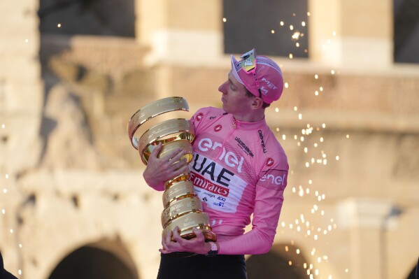 Tour of Italy winner Slovenia's Tadej Pogacar holds the trophy during the podium ceremony at the end of the 21st and last stage of the Giro D'Italia, cycling race, in Rome, Sunday, May 26, 2024. (AP Photo/Andrew Medichini)
