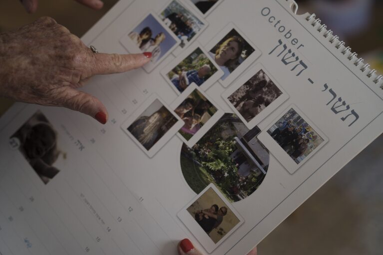 Tami Halevi, 86, talks about a calendar with pictures of her family and her house in Kibbutz Nahal Oz, as she stays in an apartment in Bat Yam, Israel, Friday, Feb. 9, 2024. (AP Photo/Leo Correa)