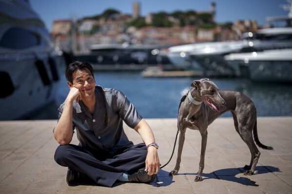 Eddie Peng poses with his dog Xin during an interview for the film 'Black Dog' at the 77th international film festival, Cannes, southern France, Tuesday, May 21, 2024. (Photo by Andreea Alexandru/Invision/AP)