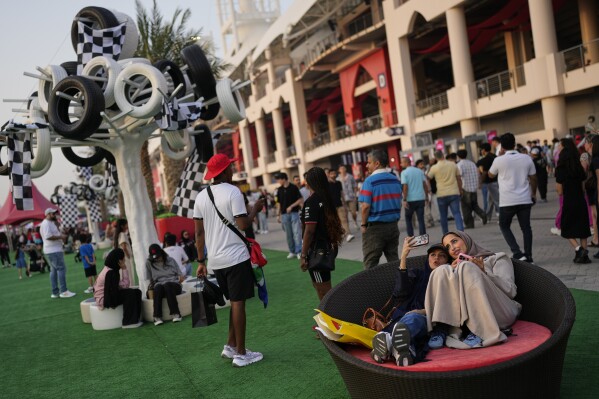 Bahraini women take a selfie as they sit on a couch at the Formula One Bahrain Grand Prix Village at the Bahrain International Circuit in Sakhir, Bahrain, Friday, April 11, 2025. (AP Photo/Altaf Qadri)