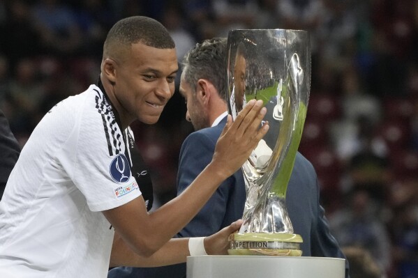 Real Madrid's Kylian Mbappe touches the trophy during the medal ceremony for the UEFA Super Cup Final soccer match between Real Madrid and Atalanta at the Narodowy stadium in Warsaw, Poland, Wednesday, Aug. 14, 2024. (AP Photo/Czarek Sokolowski)