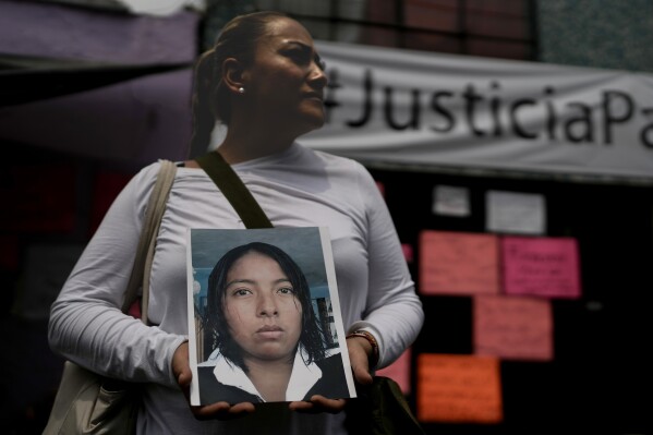 Alejandra Jiménez holds an image of Amarirany Roblero who went missing 12 years ago, during a protest outside an apartment rented by a suspected serial killer, in the Iztacalco neighborhood of Mexico City, Friday, April 26, 2024. Protesters covered the facade of the building with placards after investigators found the bones, cell phones and ID cards of several women at rented rooms there, asking variants of a single question: Why did it take prosecutors 12 years to investigate the disappearance of Amairany Roblero, then 18. (AP Photo/Marco Ugarte)