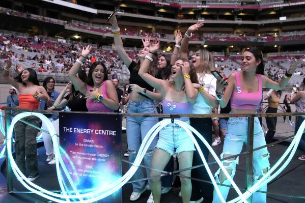 Concertgoers dance during Coldplay's Music of the Spheres world tour on Thursday, May 12, 2022, at State Farm Stadium in Glendale, Ariz. The band has included energy-storing stationary bikes to their latest world tour, encouraging fans to help power the show as part of a push to make the tour more environmentally friendly. (Photo by Rick Scuteri/Invision/AP)
