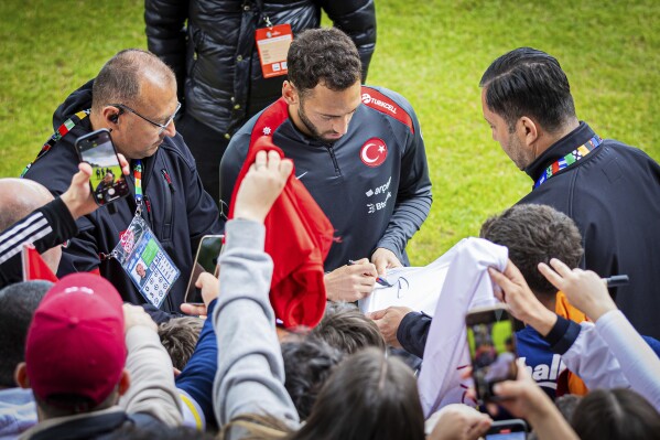 Turkey's Hakan Çalhanoglu signs autographs during training session ahead of the Euro 2024 soccer tournament in Barsinghausen, Germany, Wednesday, June 12, 2024. (Moritz Frankenberg/dpa via AP)