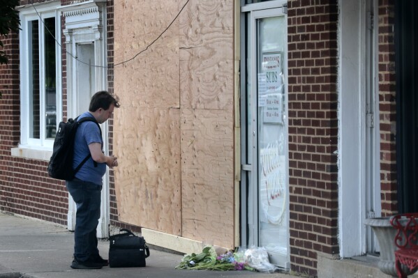 A man stops near a memorial outside Fontano's Subs in Hinsdale, Ill., on Friday, July 21, 2023. A 14-year-old boy who was critically injured when an SUV crashed into the suburban Chicago restaurant, injuring four other people, has died days after the crash, authorities said Friday.(Antonio Perez/Chicago Tribune via AP)
