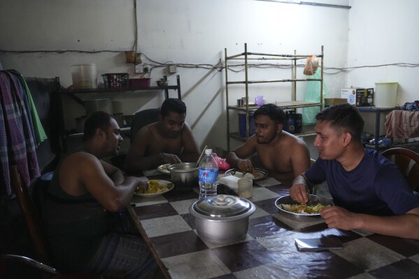 Bangladeshi migrant workers eat a meal at their dormitory in Klang, Malaysia, Friday, Jan. 24, 2025. (AP Photo/Azneal Ishak).