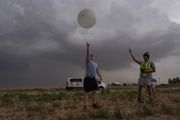Red team and Project ICECHIP members Wyatt Ficek, left, and Ethan Mok, right, release a latex weather balloon with an attached instrument called a windsond into the inflow region of a storm to collect data during a Project ICECHIP operation Thursday, June 5, 2025, near Morton, Texas. (AP Photo/Carolyn Kaster)