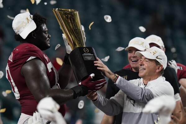 FILE -Alabama head coach Nick Saban and offensive lineman Alex Leatherwood hold the trophy after their win against Ohio State in an NCAA College Football Playoff national championship game, Tuesday, Jan. 12, 2021, in Miami Gardens, Fla. Nick Saban, the stern coach who won seven national championships and turned Alabama back into a national powerhouse that included six of those titles in just 17 seasons, is retiring, according to multiple reports, Wednesday, Jan. 10, 2024. (AP Photo/Chris O'Meara, File)