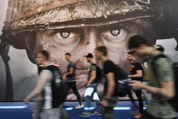 FILE - Visitors passing an advertisement for the video game 'Call of Duty' at the Gamescom fair for computer games in Cologne, Germany, Aug. 22, 2017. Microsoft has signed an agreement with Sony to keep the “Call of Duty” video game series on PlayStation following the tech giant’s acquisition of the video game maker Activision Blizzard. The announcement was made Sunday, July 16, 2023 in a Twitter post by Phil Spencer, who heads up Microsoft’s Xbox. (AP Photo/Martin Meissner, File)