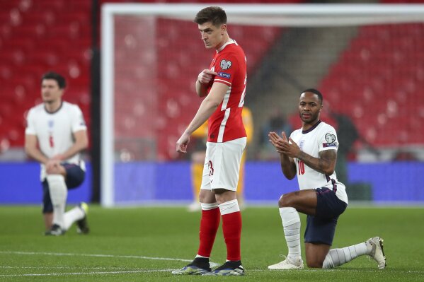 Poland's Krzysztof Piatek points to the 'Respect' badge on his sleeve as England's Raheem Sterling takes the knee before the World Cup 2022 group I qualifying soccer match between England and Poland at Wembley stadium in London, England, Wednesday, March 31, 2021. (Catherine Ivill, Pool via AP)