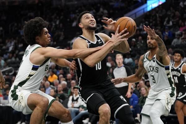 Brooklyn Nets' Ben Simmons, middle, is fouled as he drives between Milwaukee Bucks' MarJon Beauchamp, left, and George Hill, right, during the first half of an NBA preseason basketball game Wednesday, Oct. 12, 2022, in Milwaukee. (AP Photo/Aaron Gash)