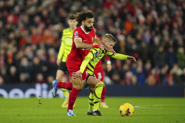 Liverpool's Mohamed Salah, left, and Arsenal's Oleksandr Zinchenko fight for the ball during the English Premier League soccer match between Liverpool and Arsenal at Anfield stadium in Liverpool, England, Saturday, Dec. 23, 2023. (AP Photo/Jon Super)