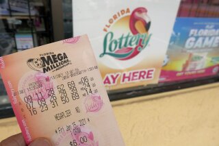 FILE - In this Wednesday, Jan. 13, 2021, file photo, a customer shows off a Mega Millions lottery ticket after purchasing it, in Orlando, Fla. The nation’s two national lottery games are designed to produce immense jackpots that generate huge sales, and the recipe certainly is working now as prizes on Thursday reached a combined $1.39 billion. The next drawing for Mega Millions is Friday night, when a $750 million prize will be up for grabs. (AP Photo/John Raoux, File)