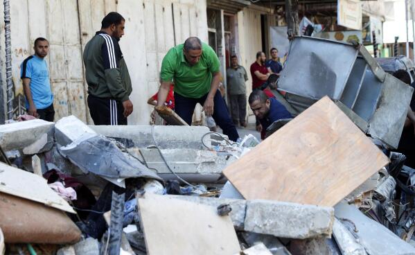 People inspect the rubble of the destroyed Abu Hussein building that was hit by an Israeli airstrike early morning, in Gaza City, Wednesday, May 19, 2021. (AP Photo/Adel Hana)
