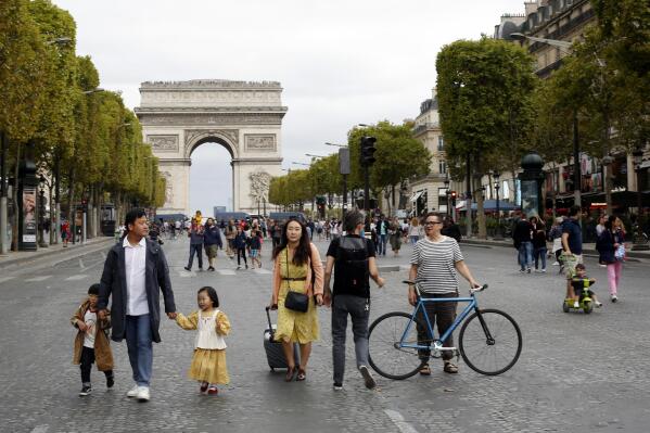 FILE - People walk on the champs Elysees avenue during the "day without cars", with the Arc de Triomphe in background, in Paris, on Sept. 22, 2019. Conservatives and conspiracy theorists are increasingly convinced the concept of a “15-minute city” is the latest nefarious plot to curtail individual freedoms. But urban experts and city officials say the design principle -- recently embraced by cities including Oxford, England, Paris, and Cleveland, Ohio -- is simply about building more compact, walkable communities where people are less reliant on cars. (AP Photo/Thibault Camus, File)