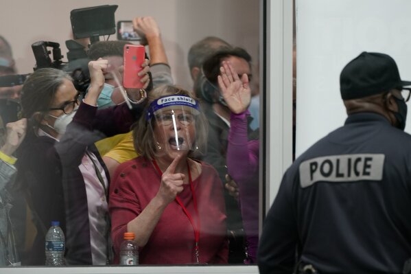 People yell as they look through the windows of the central counting board as police were helping to keep others from entering due to overcrowding, Wednesday, Nov. 4, 2020, in Detroit. (AP Photo/Carlos Osorio)
