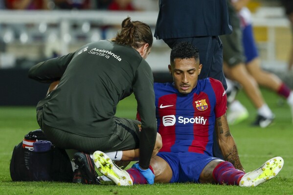 Barcelona's Raphinha receives medical treatment during a Spanish La Liga soccer match between Barcelona and Sevilla, at the Olympic Stadium of Montjuic in Barcelona, Spain, Friday, Sept. 29, 2023. (AP Photo/Joan Monfort)