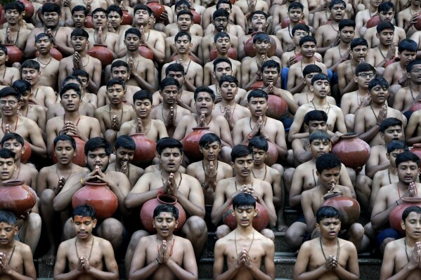 Indian students of the Swaminarayan Gurukul pray after demonstrating a ritualistic bath called Magh Snan for the media in Ahmedabad, India, Wednesday, Jan. 24, 2024. Devotees believe that a purification bath taken during the auspicious Hindu calendar month of Magh, which begins Thursday, will absolve them of their sins. (AP Photo/Ajit Solanki)