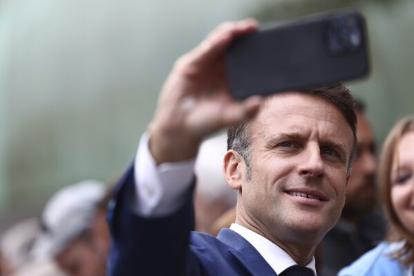 French President Emmanuel Macron takes a selfie with supporters after voting in Le Touquet-Paris-Plage, northern France, Sunday, June 30, 2024. (Yara Nardi, Pool via AP)