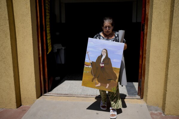 Rita Canteros walks out of a parish church carrying a painting of Mar铆a Antonia de Paz y Figueroa, more commonly known by her Quechua name of 鈥淢ama Antula,鈥� on the outskirts of Buenos Aires, Argentina, Sunday, Jan. 28, 2024. The canonization of 鈥淢ama Antula鈥� in a Feb. 11th ceremony to be presided by Pope Francis at St. Peter's Basilica marks the first time a female from Argentina will become saint. (APPhoto/Natacha Pisarenko)
