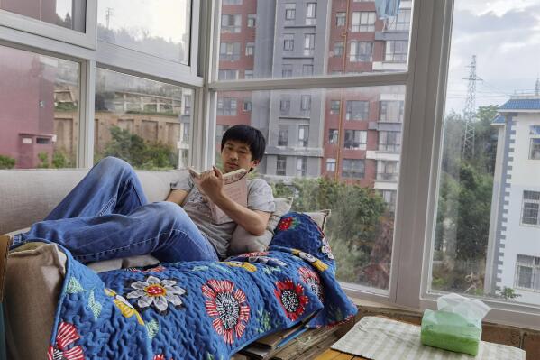 In this photo released by Guo Jianlong, Guo reads a book at the balcony of his home in Dali in southwestern China's Yunnan province on June 29, 2021. Guo joined a small but visible handful of Chinese urban professionals who are rattling the ruling Communist Party by choosing to "lie flat," or reject grueling careers for what they call a "low-desire life." That is clashing with the ruling party's message of success and consumerism as its celebrates the 100th anniversary of its 1921 founding. (Guo Jianlong via AP)