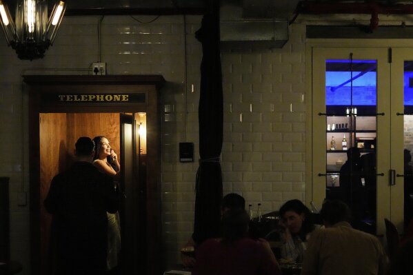Diners stand inside the telephone booth at The Marabi Club in downtown Johannesburg, South Africa, Friday, May 9, 2025. (AP Photo/Themba Hadebe)