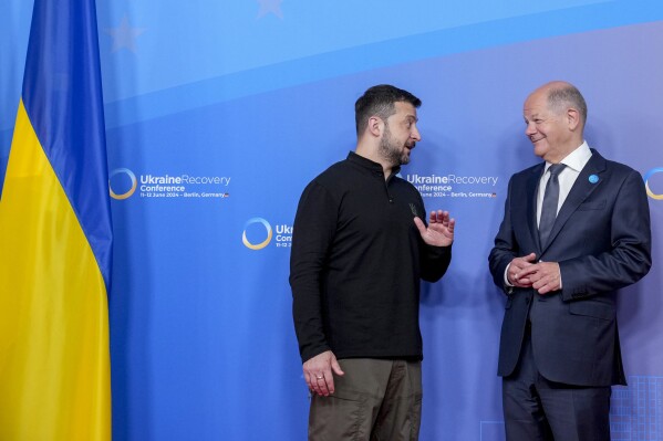 Ukrainian President Volodymyr Zelenskyy, left, and German Chancellor Olaf Scholz talk at the start of the recovery conference in Berlin, Germany, Tuesday, June 11, 2024. Germany is hosting a conference to gather support for Ukraine's recovery from the destruction wreaked by Russia's war, sending a new signal of solidarity with Kyiv at the start of a week of intense diplomacy. (AP Photo/Ebrahim Noroozi)