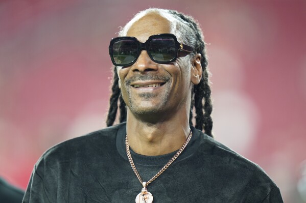 FILE - Entertainer Snoop Dogg walks on the field before an NFL football game between the Tampa Bay Buccaneers and the New Orleans Saints Sunday, Dec. 19, 2021, in Tampa, Fla. Snoop Dogg will serve as a primetime NBC correspondent for Paris Olympics. (AP Photo/Chris O'Meara, File)