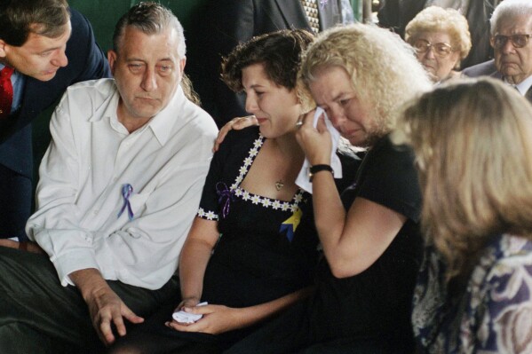Aren Almon, center, whose daughter Baylee became a national symbol in an iconic photo of a firefighter holding her lifeless body following the bombing of the federal building in Oklahoma City, is comforted by her father Tommy Almon and mother Debbie Almon, during a funeral service for Baylee at Arlington Memorial Park Cemetery in Oklahoma City, April 24, 1995. (AP Photo/Pat Sullivan, File)