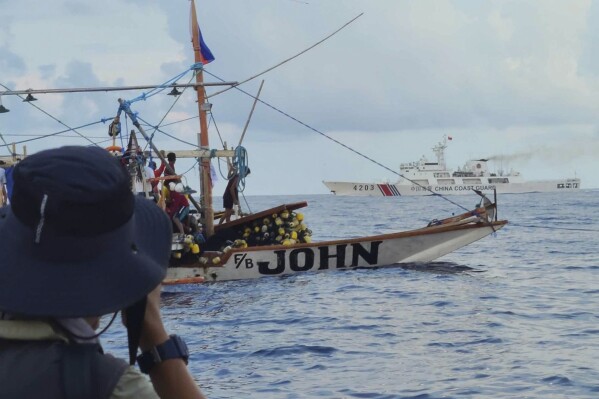 In this photo provided by Atin-Ito/Akbayan Party, a Chinese Coast Guard ship, background, passes the boats of activists and volunteers from a nongovernment coalition called Atin Ito, Tagalog for This is Ours, at the South China Sea on Thursday May 16, 2024. About 100 Filipino activists on wooden boats have decided not to sail closer to a fiercely disputed shoal in the South China Sea on Thursday to avoid a confrontation with dozens of Chinese coast guard and suspected militia ships guarding the area. (Atin-Ito/Akbayan Party via AP)