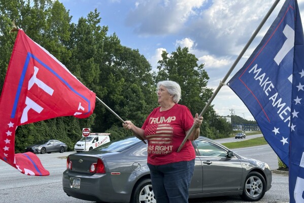 Suzanne Brown waves flags for Donald Trump before a ceremony to open his first Georgia campaign office, Thursday, June 13, 2024, in Fayetteville, Ga. Democratic President Joe Biden and former Republican President Donald Trump are working to win over Georgia voters ahead of the pair's first 2024 debate scheduled for Thursday, June 27, in Atlanta. (AP Photo/Jeff Amy) 