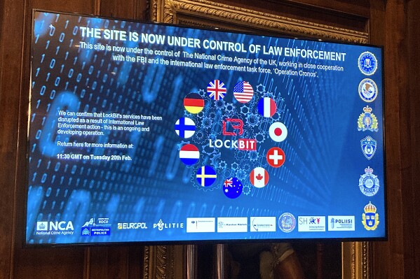 A TV screen shows the front page of LockBit's dark-web leak site that was replaced with the words "this site is now under control of law enforcement," alongside the flags of the U.K., the U.S. and several other nations during the law enforcement press conference to outline the details of a law enforcement operation against the ransomware syndicate LockBit in London, Tuesday, Feb. 20, 2024. Law-enforcement agencies said they infiltrated and disrupted LockBit, arresting two people involved with the prolific ransomware syndicate that has extracted $120 million from thousands of victims around the world. (APPhoto/Kelvin Chan)