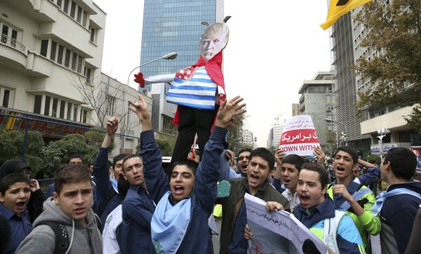 
              FILE- In this Nov. 4, 2017 file photo, Iranian schoolboys chant slogan while holding an effigy of U.S. President Donald Trump in an annual gathering in front of the former U.S. Embassy marking the anniversary of its 1979 takeover in Tehran, Iran. President Donald Trump is weighing whether to pull the U.S. out of Iran's nuclear deal, a 2015 agreement that capped over a decade of hostility between Tehran and the West over its atomic program. (AP Photo/Vahid Salemi, File)
            