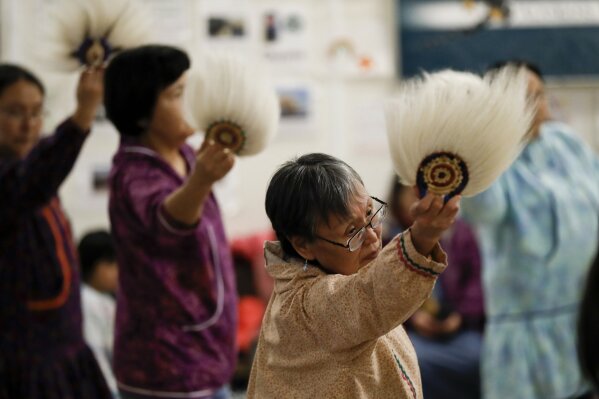 In this Jan. 20, 2020 photo, Mary Acosta, center, takes part in an Alaska Native dance in Toksook Bay, Alaska, a mostly Yup'ik village on the edge of the Bering Sea. Census workers traditionally begin the official decennial count in rural Alaska when the ground is still frozen. That allows easier access before the spring melt makes many areas inaccessible to travel and residents scatter to subsistence hunting and fishing grounds. The rest of the nation, including more urban areas of Alaska, begin the census in mid-March. (AP Photo/Gregory Bull)