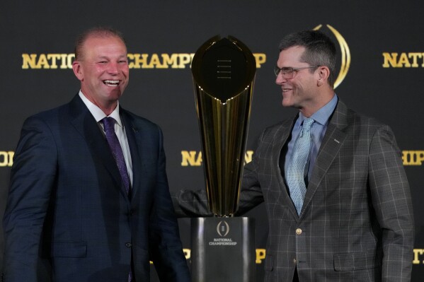 Washington head coach Kalen DeBoer, left, and Michigan head coach Jim Harbaugh pose with the trophy after a news conference ahead of the national championship NCAA College Football Playoff game between Washington and Michigan Sunday, Jan. 7, 2024, in Houston. The game will be played Monday. (AP Photo/David J. Phillip)