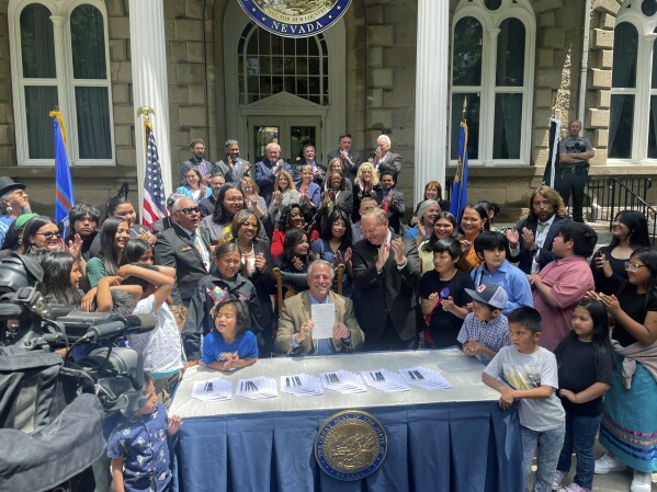 Nevada Gov. Joe Lombardo smiles after signing a bill to provide more rural and tribal school funding, flanked by dozens of legislators, tribal members and students outside the state Capitol building on Tuesday, June 13, 2023, in Carson City, Nev. The new legislation also funds a new Owyhee Combined School School on the Duck Valley Indian Reservation along the Nevada-Idaho border. (AP Photo/Gabe Stern)