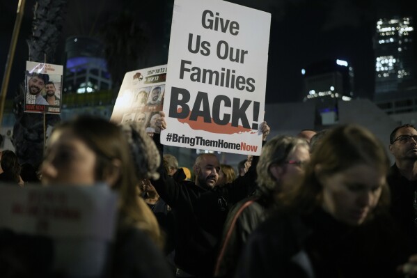 A man holds a sign calling for the release of the hostages taken by Hamas militants into the Gaza Strip during a demonstration at the Hostages Square in Tel Aviv, Israel, Saturday Jan. 13, 2024. Sunday marks 100 days that Israel and Hamas have been at war after Hamas' cross-border attack on Oct. 7 in which the group killed some 1,200 people, mostly civilians, and took 250 others hostage. In the Gaza Strip, health authorities say the death toll already has eclipsed 23,000 people.(AP Photo/Leo Correa)