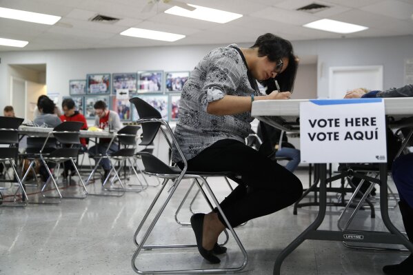 FILE - In this Feb. 15, 2020, file photo, a woman votes at an early voting location at the culinary workers union hall  in Las Vegas. Nevada Democrats are hoping to avoid a repeat of the chaos that ensnared the Iowa caucuses, as voters gather across the Silver State on Saturday to make their presidential preferences known. Iowa's process cratered this month following a rushed effort by state Democrats to deploy a mobile app for caucus volunteers to report results. Democrats in Nevada were going to use the same app developer as Iowa did, but quickly sidelined those plans. They will still be relying to some extent on technology to assist in counting and reporting results, though, and like Iowa, they will have paper backups. (AP Photo/John Locher, File)