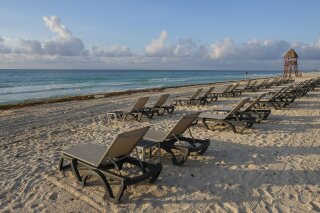 FILE - In this June 11, 2020 file photo, lounge chairs fill an empty beach in Cancun, Mexico. In a bill approved unanimously Tuesday, Sept. 30, 2020, Mexico’s Senate has voted to levy fines of up to $47,000 against hotels, restaurants or other property owners who restrict access to the country’s beaches. (AP Photo/Victor Ruiz, File)