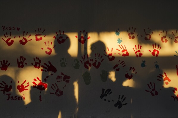 Patients' shadows are cast on a wall at a Doctors Without Borders medical clinic in Putucual, Venezuela, Wednesday, Jan. 10, 2024. A group of women and teenage girls visited the medical clinic in eastern Venezuela for free contraceptives where a community health worker taught them how to use an IUD, condoms and birth control pills correctly and about HPV infections. (AP Photo/Matias Delacroix).