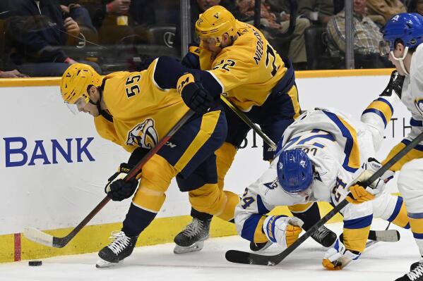 Nashville Predators defenseman Roland McKeown (55) gets control of the puck in front of right wing Nino Niederreiter (22) and Buffalo Sabres center Dylan Cozens (24) during the first period of an NHL hockey game Saturday, Jan. 14, 2023, in Nashville, Tenn. (AP Photo/Mark Zaleski)