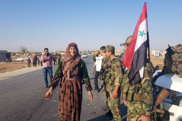 In this photo released by the Syrian official news agency SANA, residents welcome Syrian soldiers shortly after they entered the northern town of Tal Tamr on Monday, Oct 14, 2019. The move toward Tal Tamr came a day after Syria's Kurds said Syrian government forces agreed to help them fend off Turkey's invasion — a major shift in alliances that came after President Donald Trump ordered all U.S. troops withdrawn from the northern border area amid the rapidly deepening chaos. (SANA via AP)