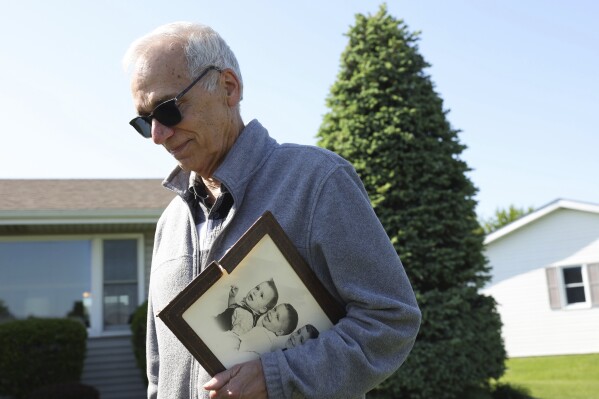 John Prevost, brother of new Pope Leo XIV, holds a portrait of the three Prevost brothers from 1958 while answering reporters' questions outside his home Thursday, May 8, 2025, in New Lenox, Ill. (John J. Kim/Chicago Tribune via AP)